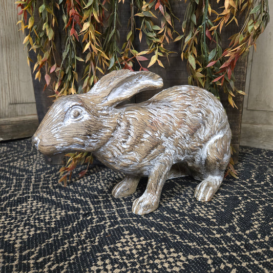 Decorative rabbit figurine on a textured surface with foliage