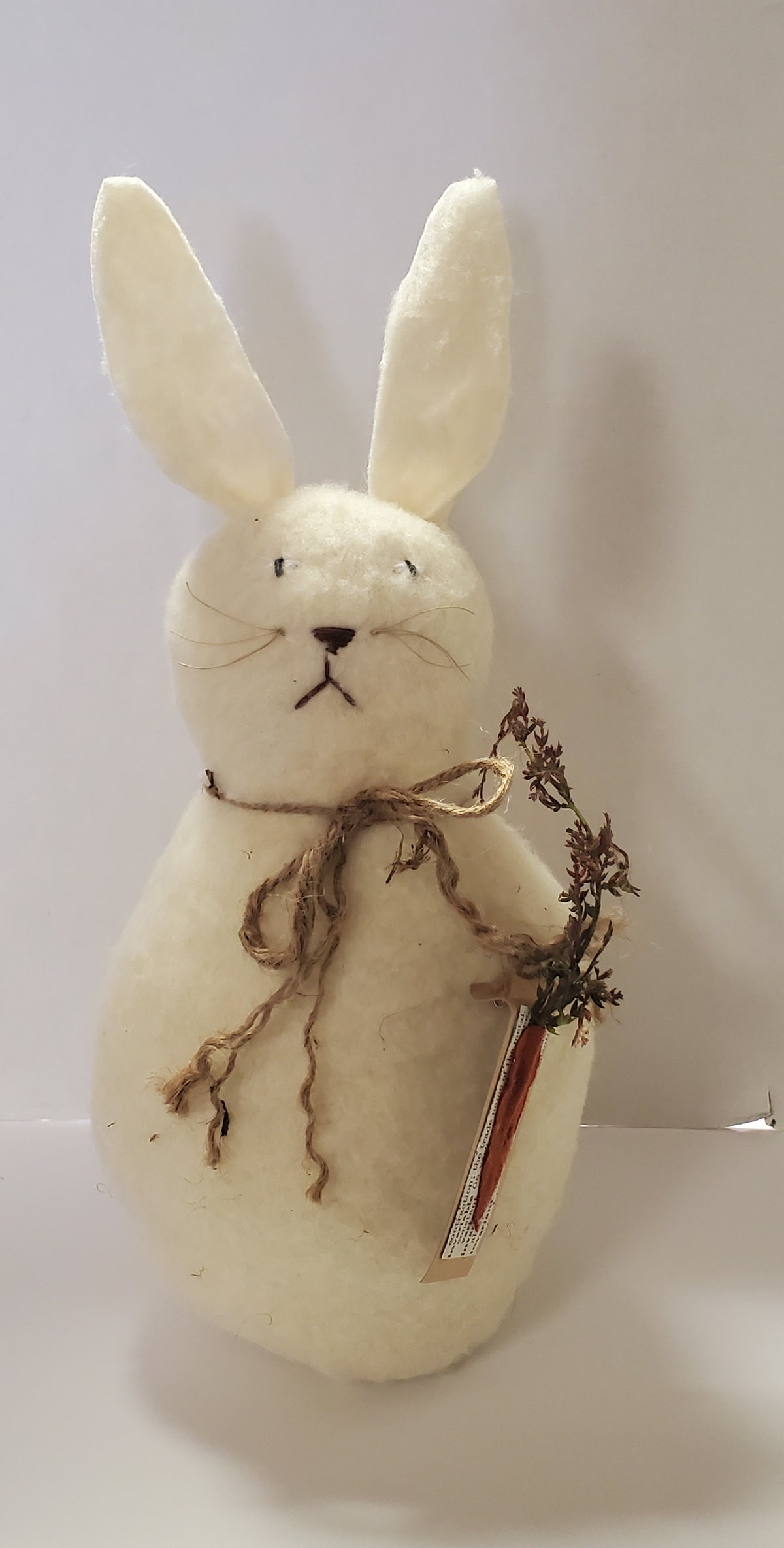 White rabbit plush toy holding a carrot on a white background
