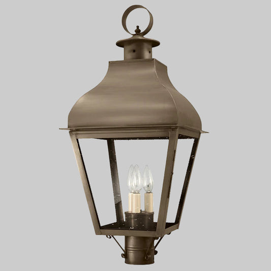 Bronze outdoor lantern with two visible light bulbs on a gray background