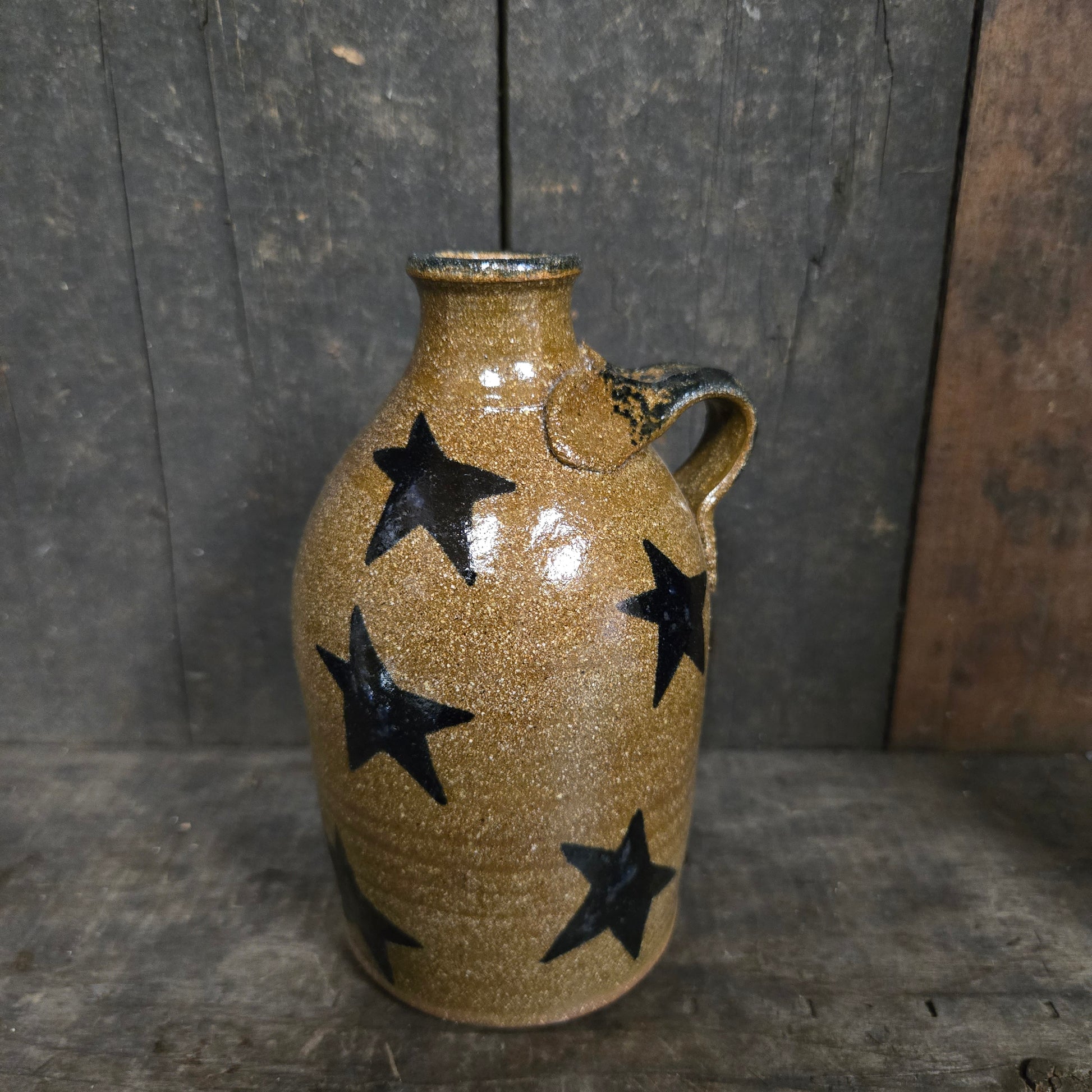 Ceramic vase with black star patterns on a wooden surface
