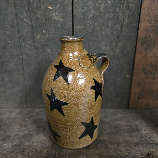 Ceramic vase with black star patterns on a wooden surface