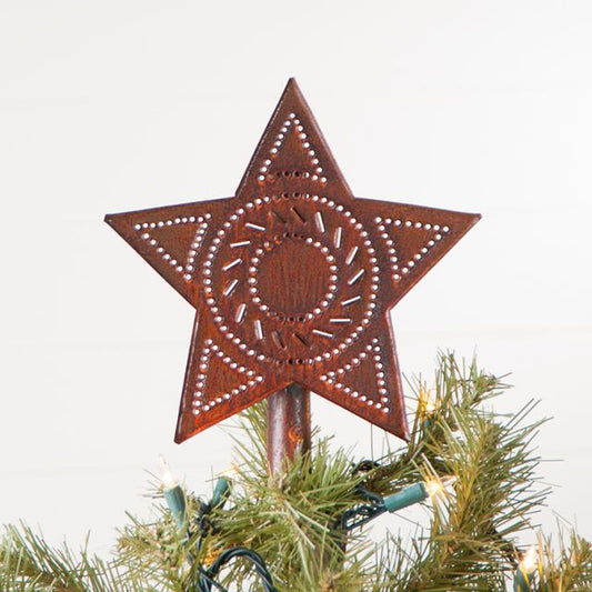 A rustic tin star-shaped tree topper with visible nail patterns, placed on a Christmas tree.