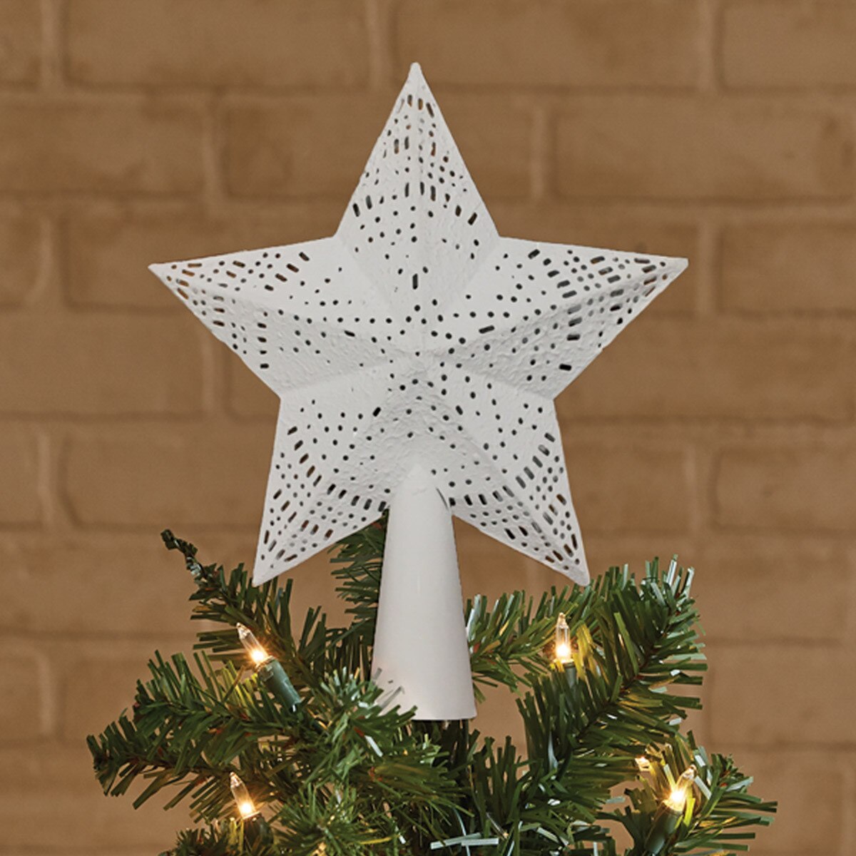 Decorative star tree topper on a Christmas tree with a brick wall background