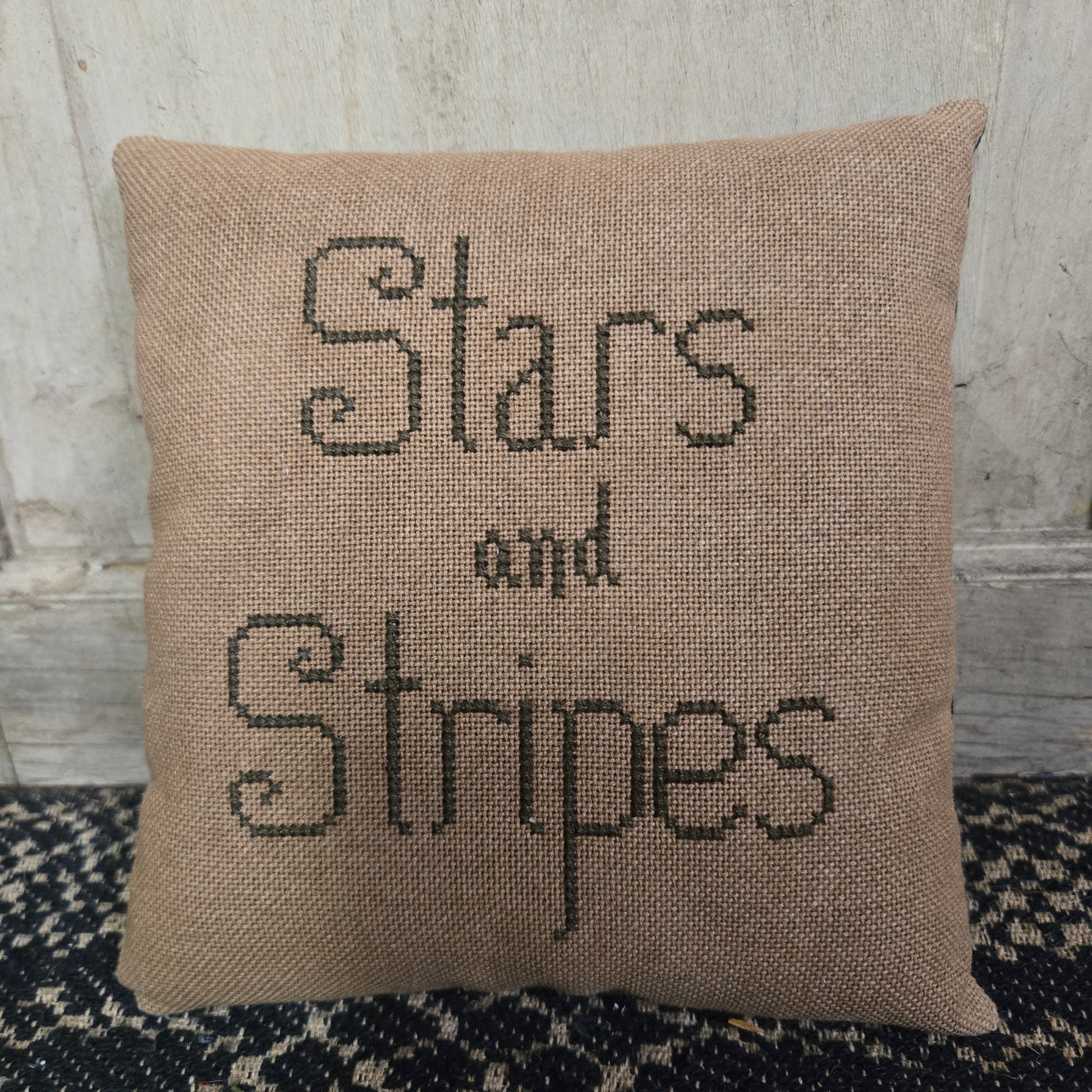 Decorative pillow with 'Stars and Stripes' text on a textured background.