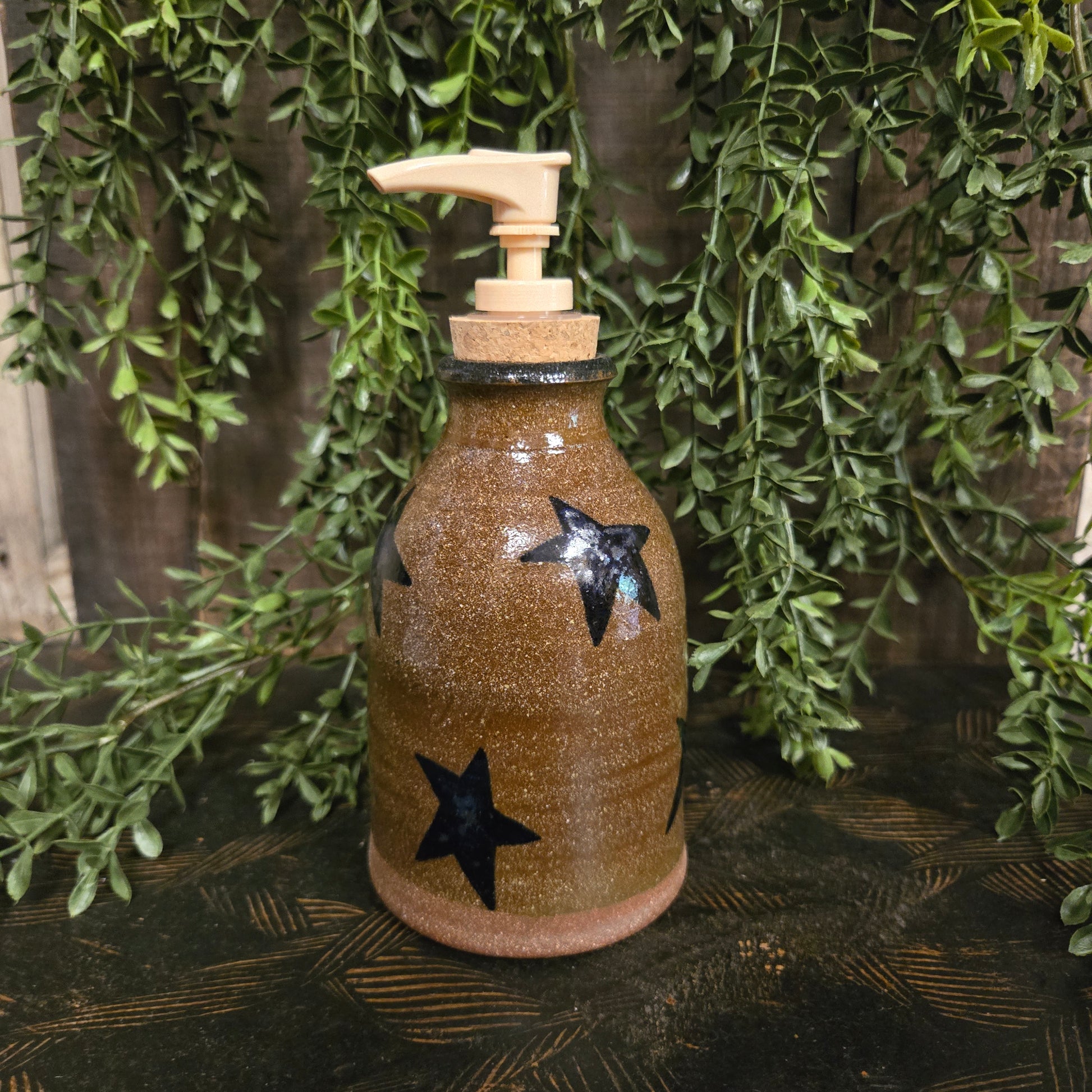Decorative bottle with star patterns on a wooden surface with greenery