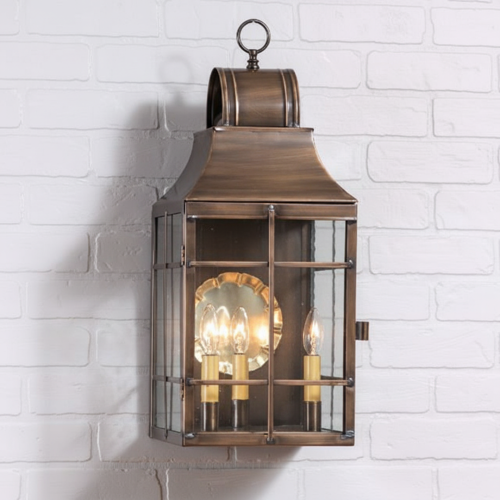 Bronze wall-mounted lantern with glass panels on a white brick wall