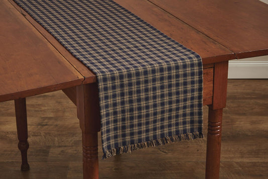 Wooden table with a blue plaid table runner on a wooden floor.