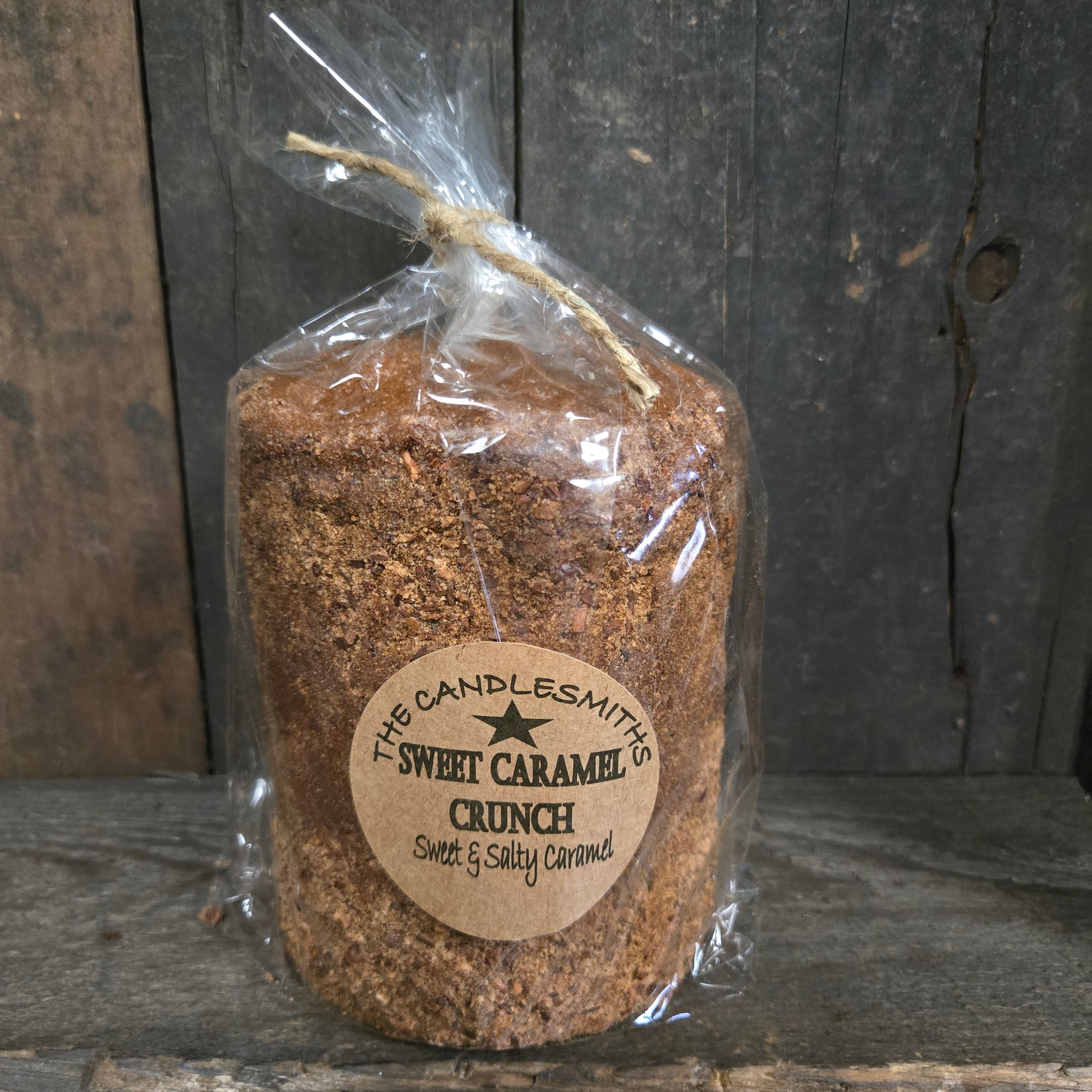 Wrapped sweet caramel crunch candle on a wood surface.