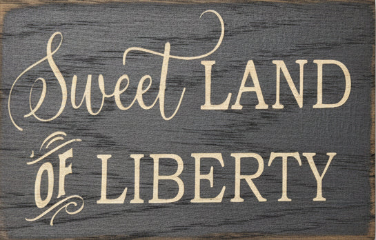 Wooden sign with 'Sweet Land of Liberty' text on a gray background