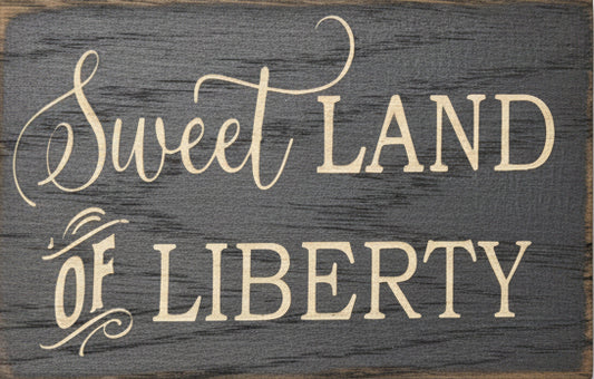 Wooden sign with 'Sweet Land of Liberty' text on a gray background