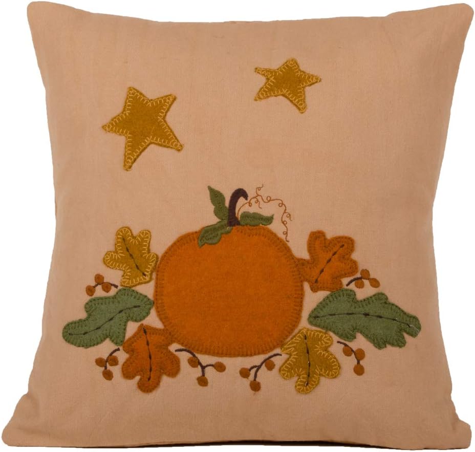 Decorative pillow with embroidered pumpkin, leaves, and stars on a beige background