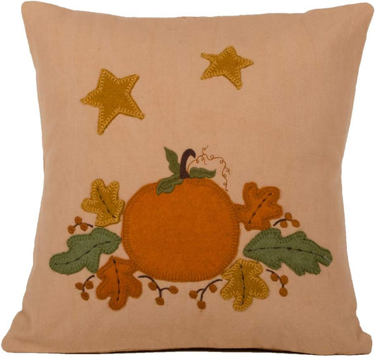 Decorative pillow with embroidered pumpkin, leaves, and stars on a beige background