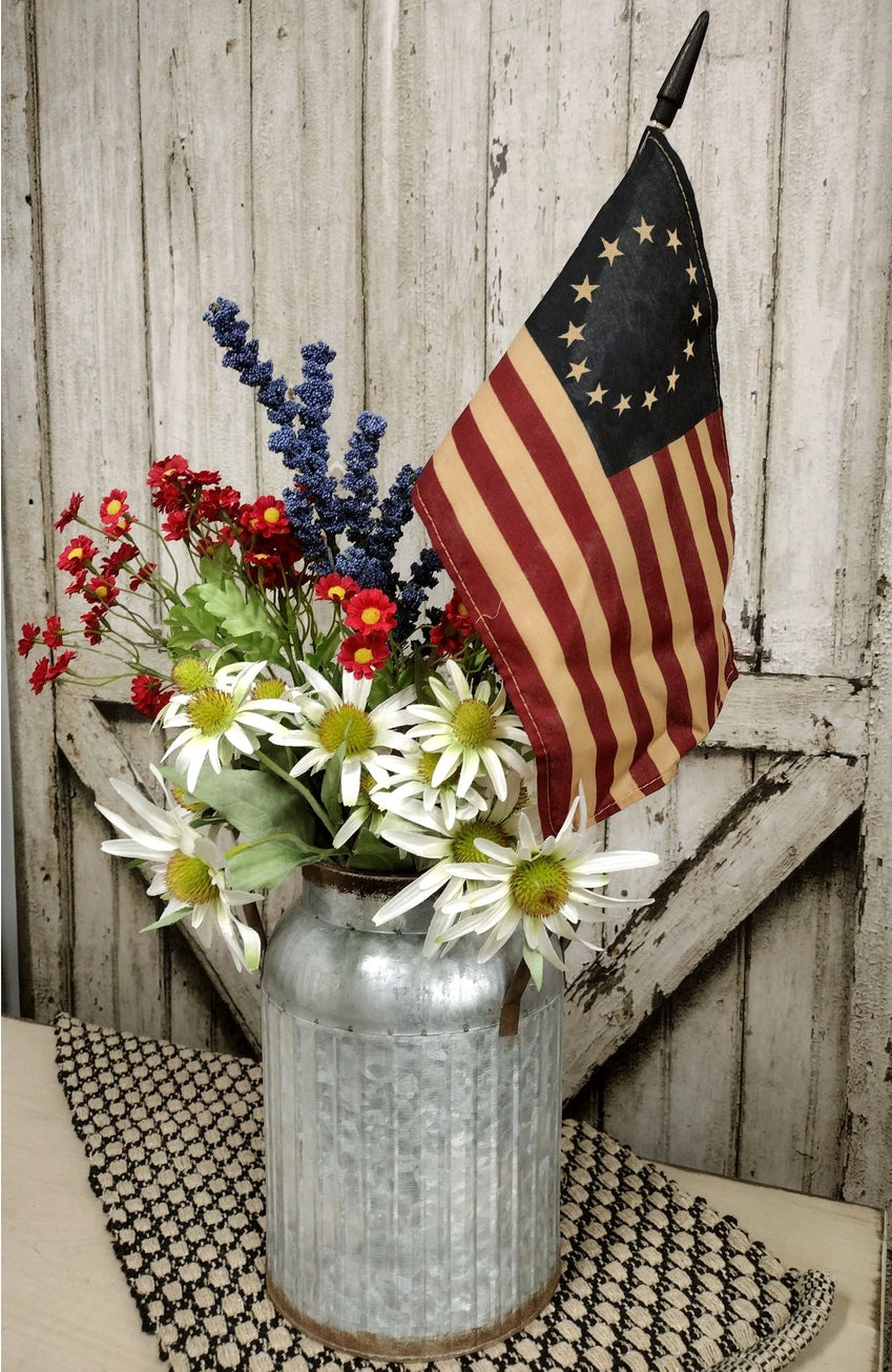Teastained flag in watering can with flowers