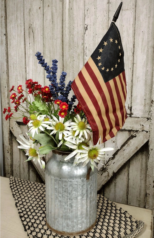 Teastained flag in watering can with flowers