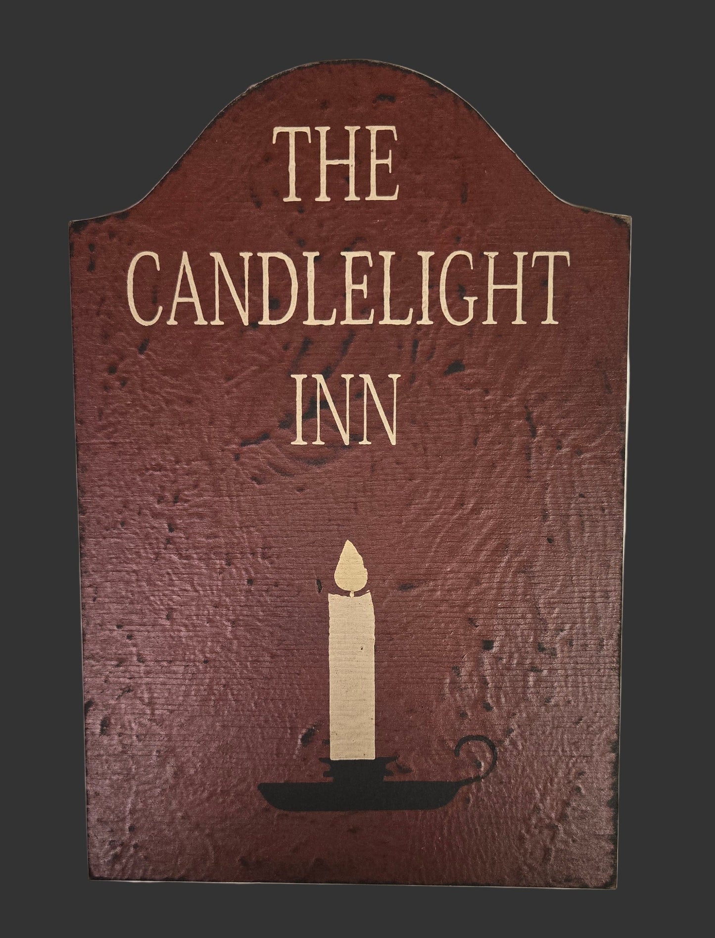 Decorative sign for 'The Candlelight Inn' with a candle illustration on a dark background