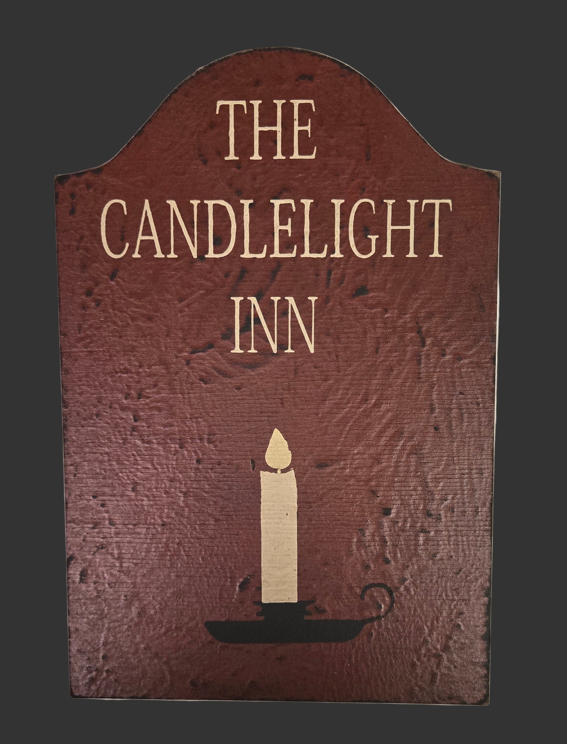 Decorative sign for 'The Candlelight Inn' with a candle illustration on a dark background