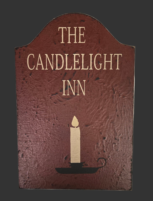 Decorative sign for 'The Candlelight Inn' with a candle illustration on a dark background