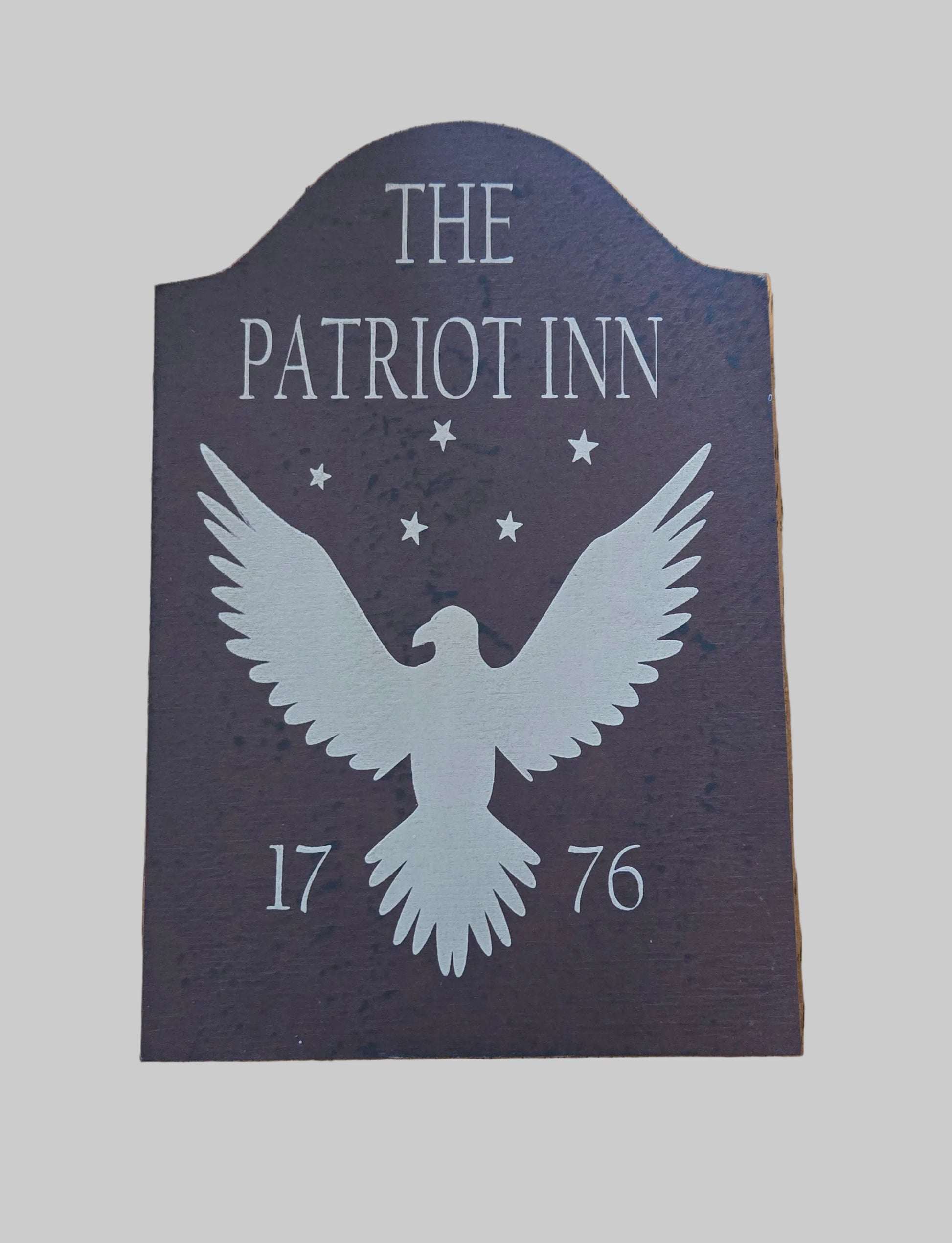 Decorative sign for 'The Patriot Inn' with an eagle silhouette and year '1776' on a gray background.