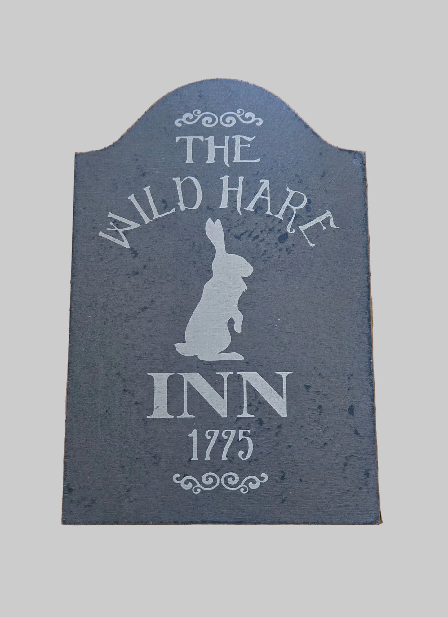 Slate sign with 'The Wild Hare Inn 1775' text and rabbit silhouette on a wooden background