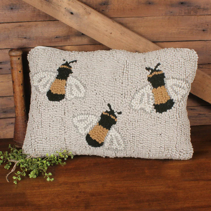 Decorative pillow with bee pattern on a wooden surface