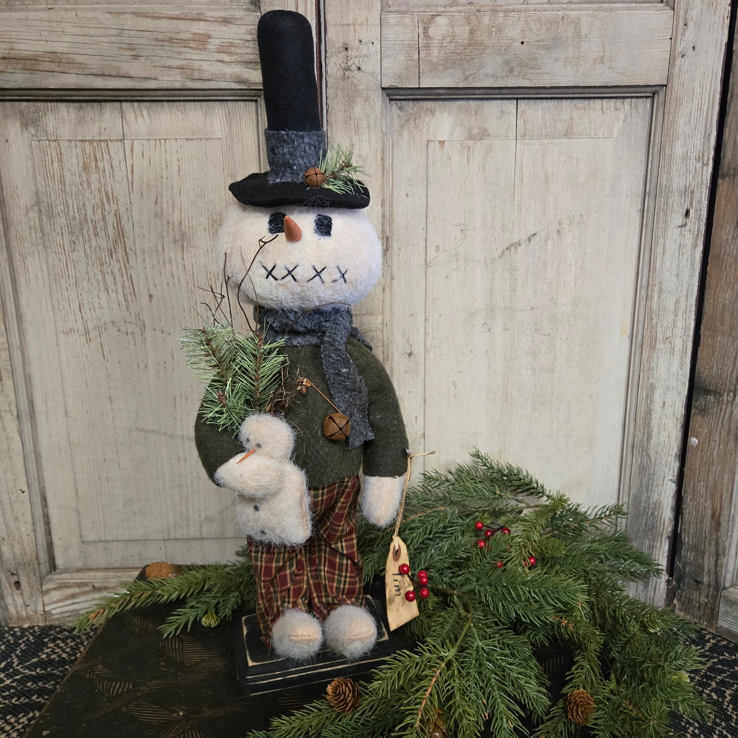 Decorative snowman figure with a tree against a wooden background