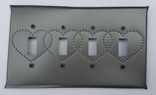 A tin quad switch plate with heart punch design, featuring a gray color and bordered by screws.