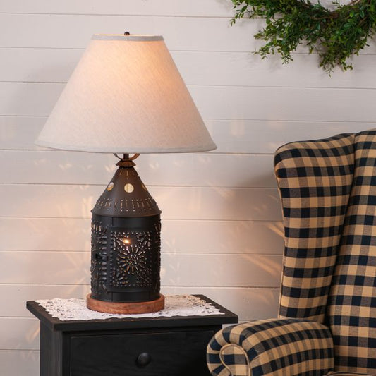 Decorative table lamp on a side table next to a plaid chair against a wooden wall.