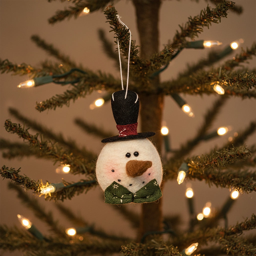 Felt snowman ornament with a top hat and green coat on a white background