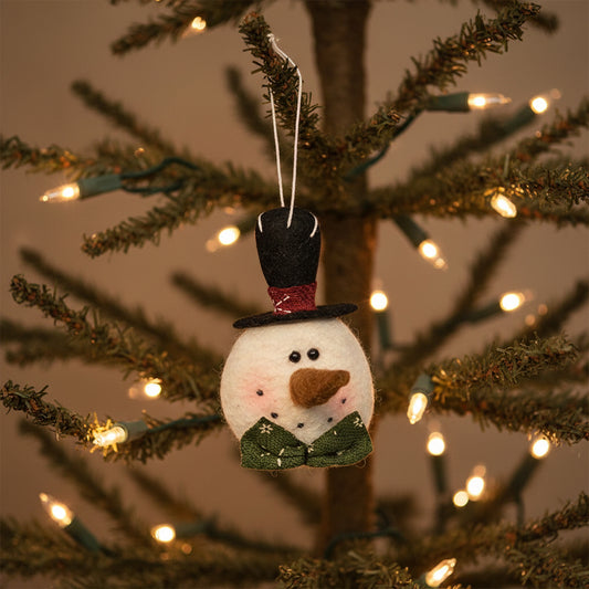 Felt snowman ornament with a top hat and green coat on a white background