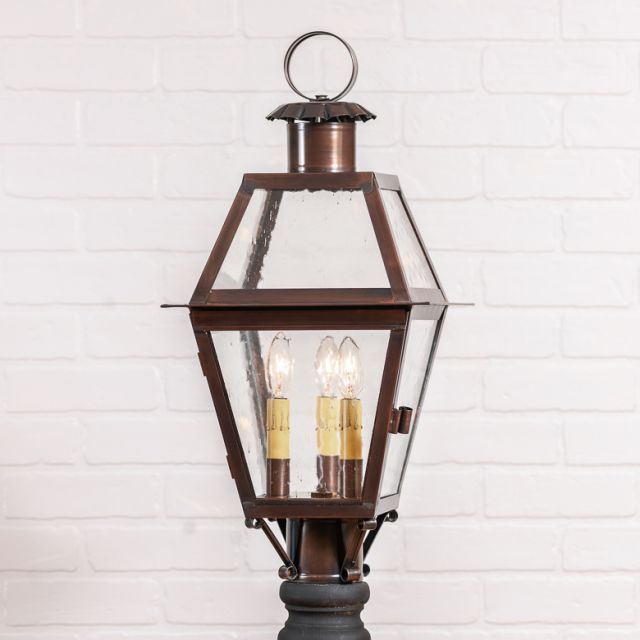 Decorative outdoor lamp with clear glass panels on a white brick wall background