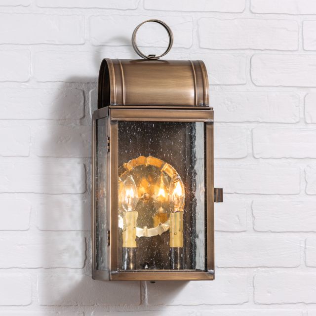 Bronze outdoor wall light fixture on a white brick wall