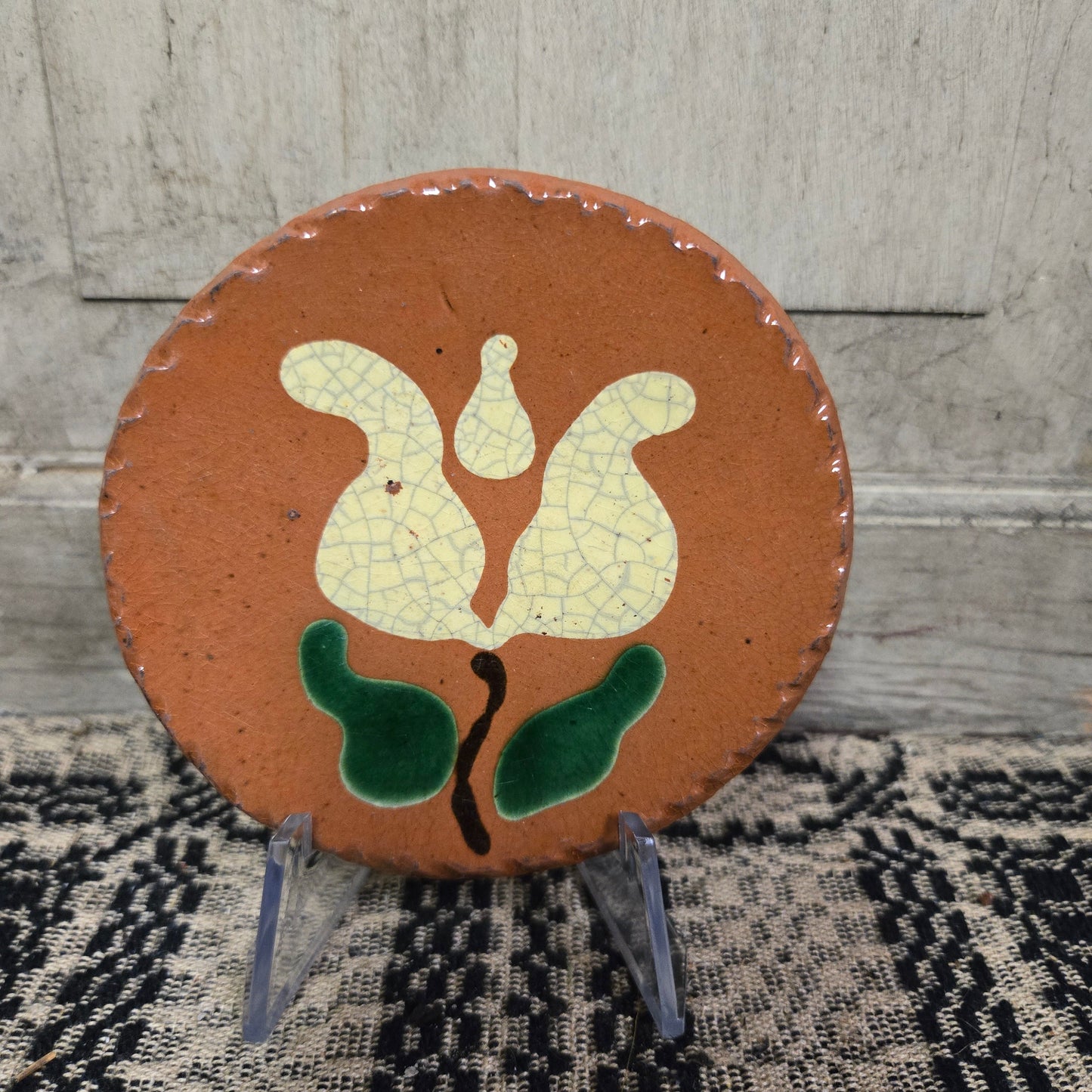 Small round redware plate with a tulip with green leaves motif