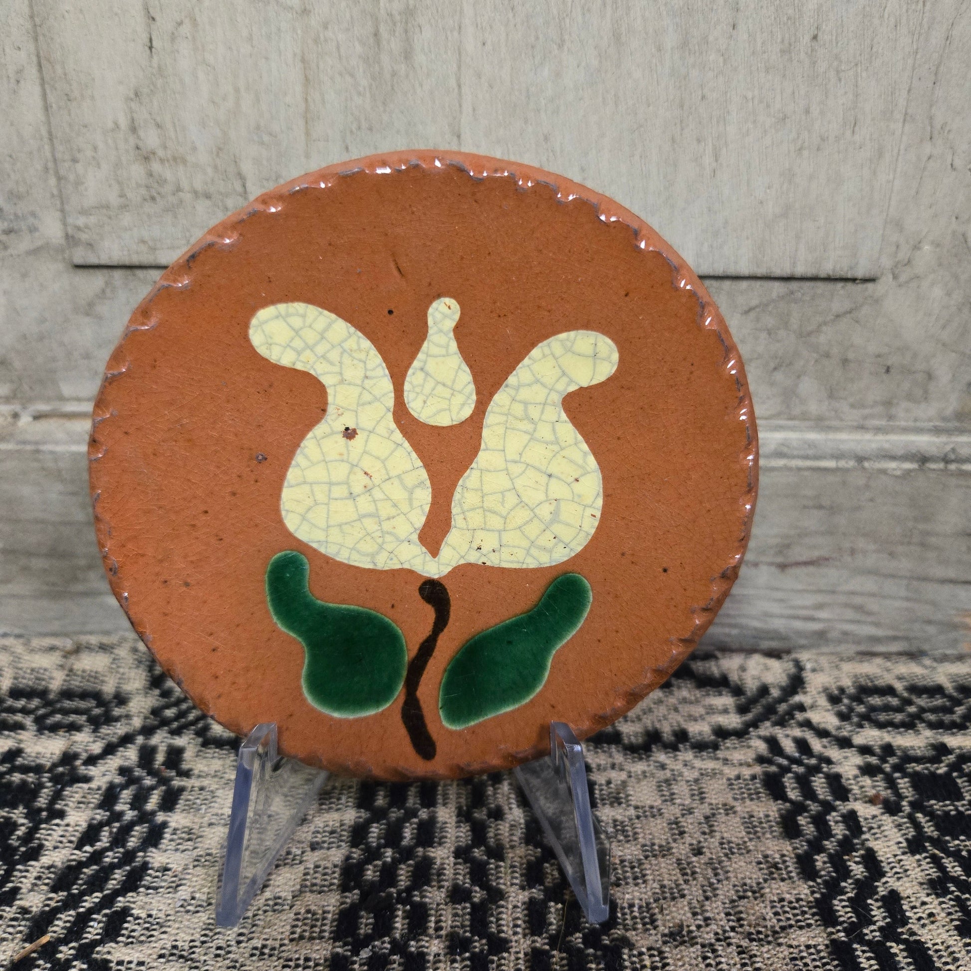 Small round redware plate with a tulip with green leaves motif