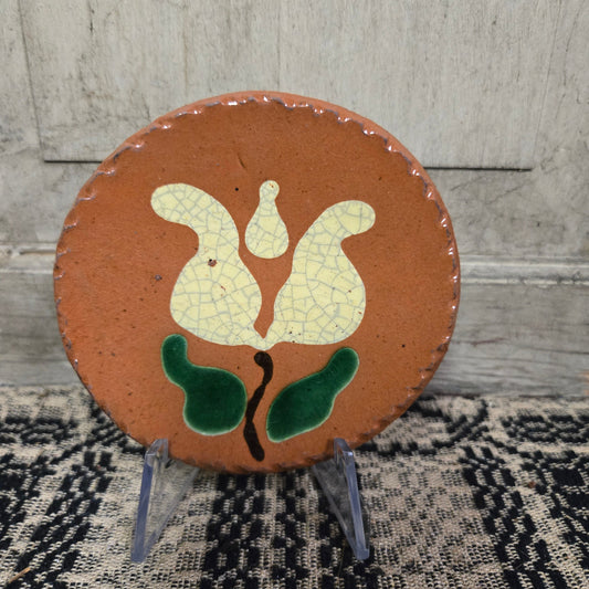 Small round redware plate with a tulip with green leaves motif