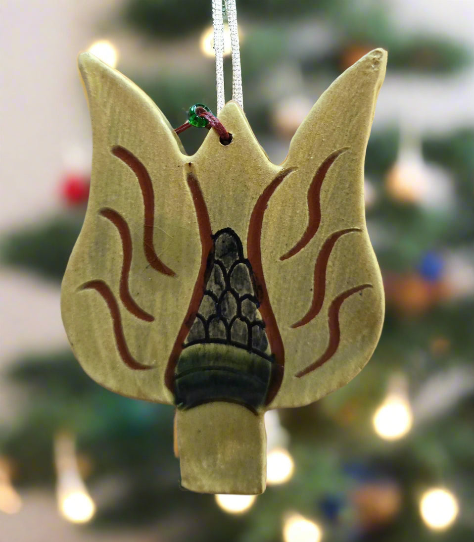 Decorative ornament shaped like a campfire with flames on a blurred Christmas tree background.