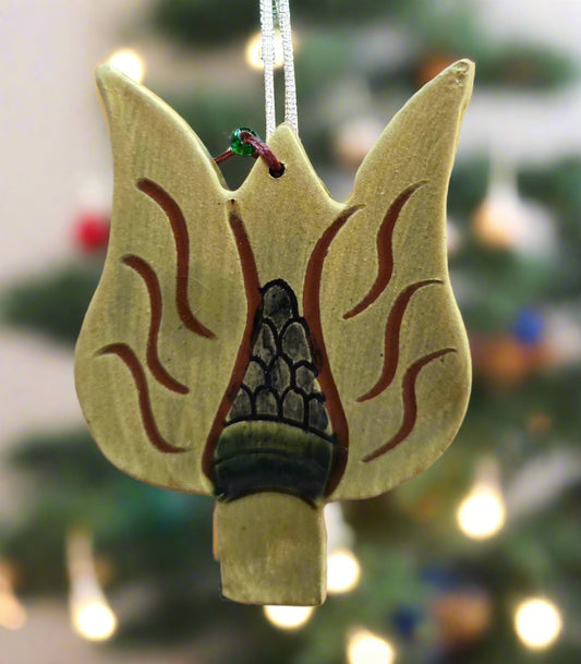 Decorative ornament shaped like a campfire with flames on a blurred Christmas tree background.