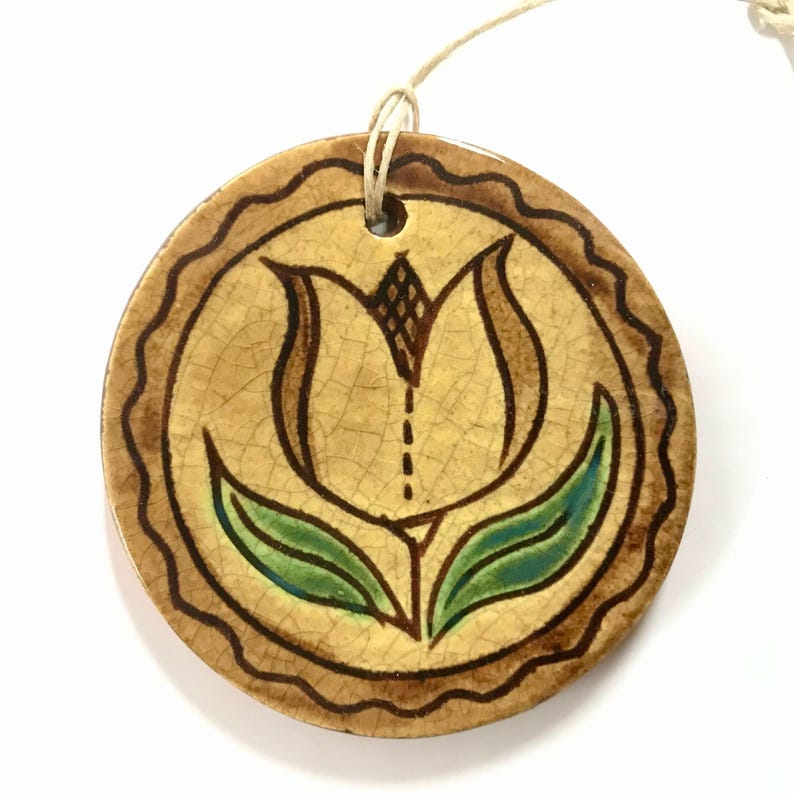 Round pottery ornament with a tulip and brown squiggle border