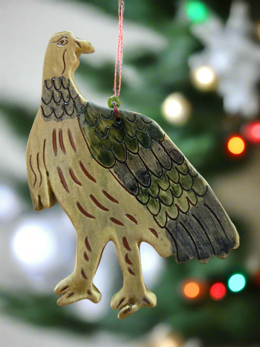 Decorative eagle ornament hanging against a blurred Christmas tree background.