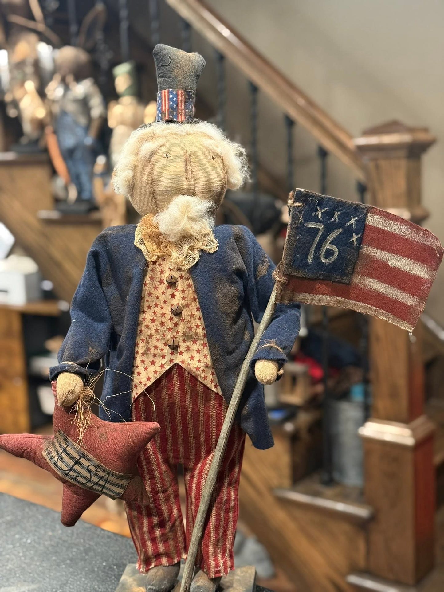 Vintage-style figure holding an American flag with a star and number 76, in a store setting.