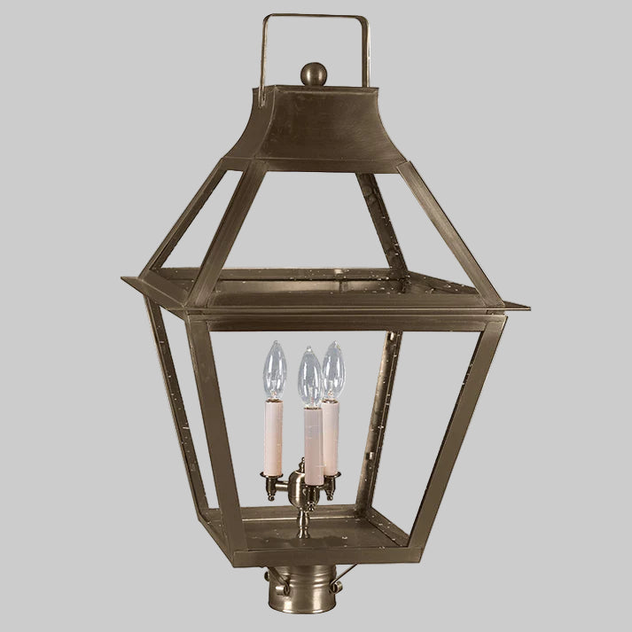 Bronze outdoor lantern with two lit candles on a gray background