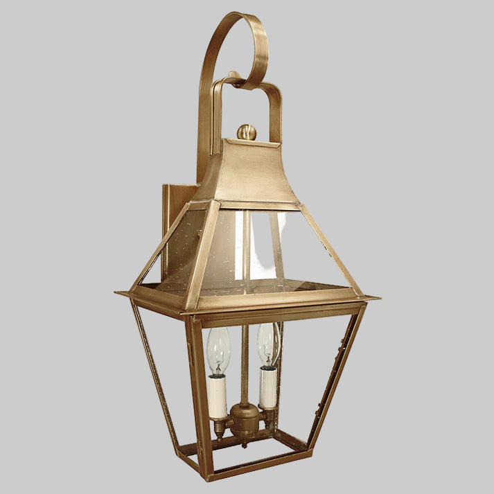 Brass wall-mounted lantern with glass panels on a gray background
