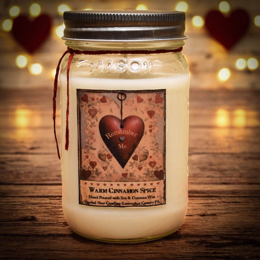 Mason jar candle labeled "Warm Cinnamon Spice" with heart artwork sitting on a wooden surface