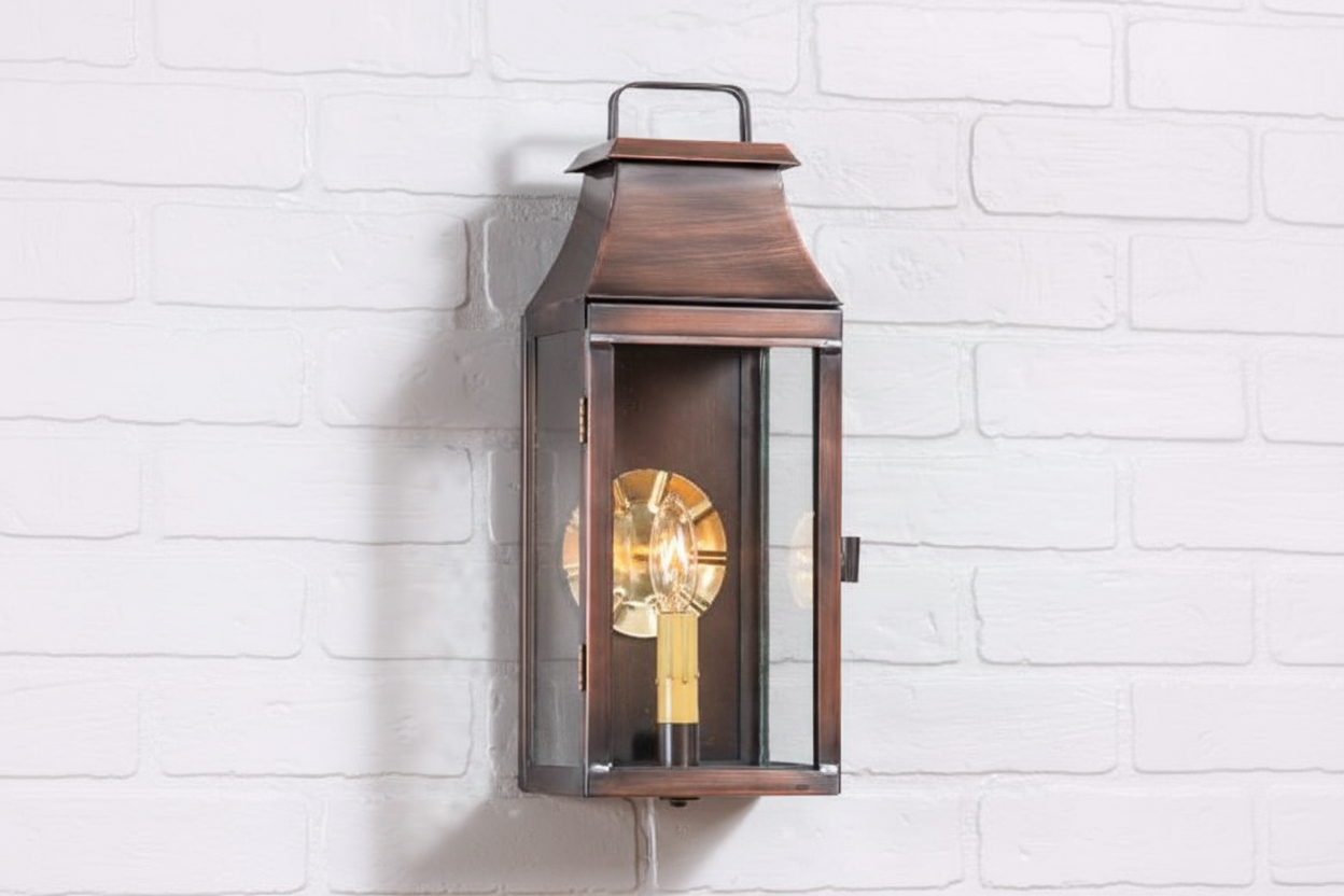 Decorative wall-mounted lantern with a light bulb inside on a white brick wall.