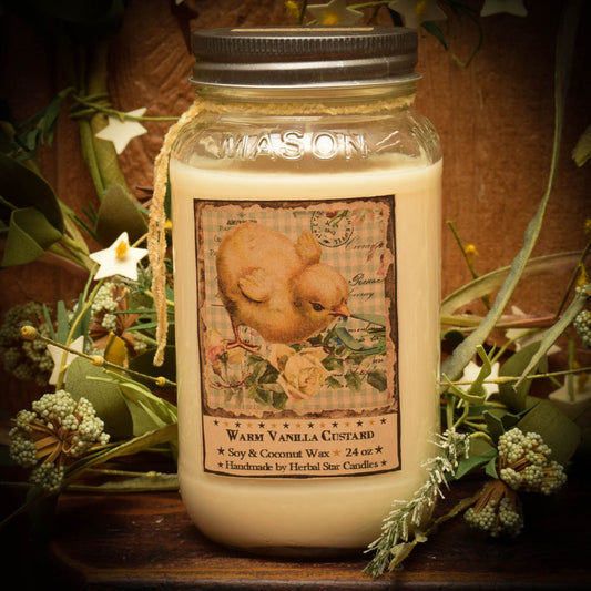 A 24 oz Mason jar candle with a 'Vanilla Custard' label and a decorative vintage-style lid, surrounded by greenery and flowers.