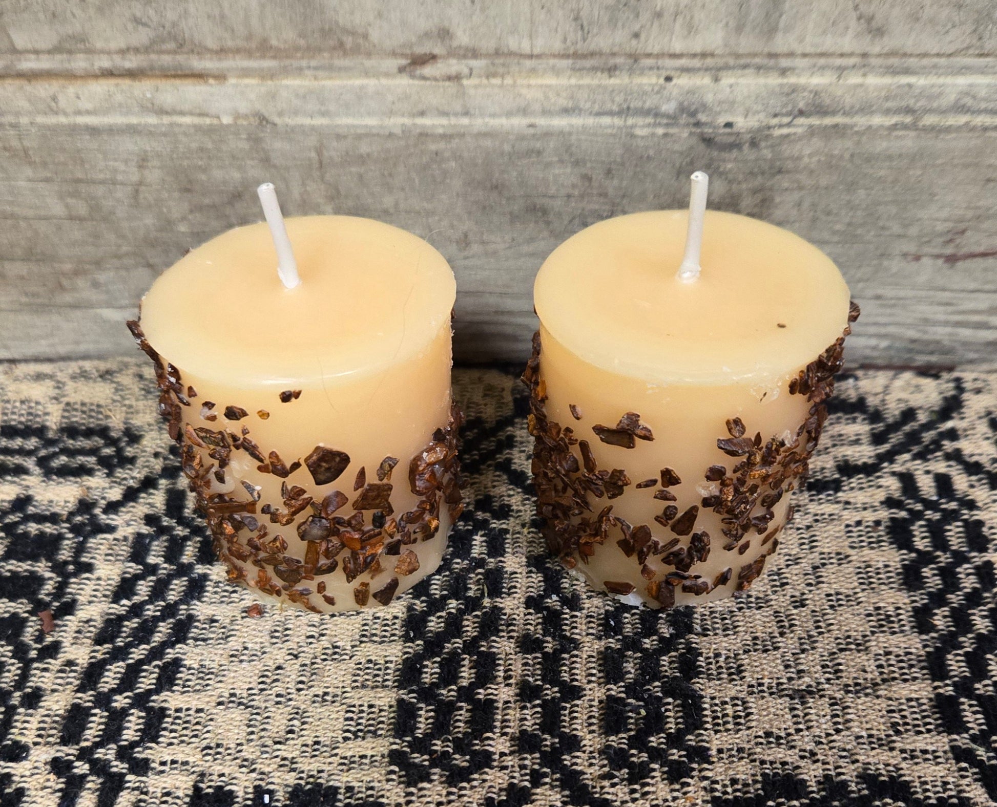 Two candles with a vanilla and hazelnut scent, placed on a textured surface.