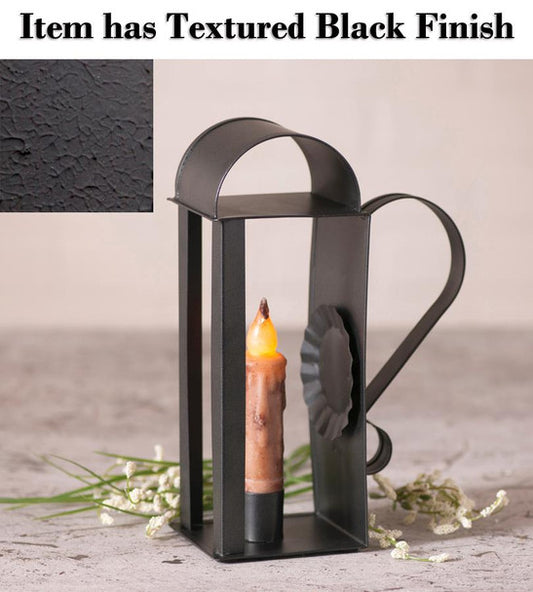 A textured black candle holder with a handle, designed to hold a battery-operated taper candle, displayed on a stone surface with a close-up inset showing the black finish.