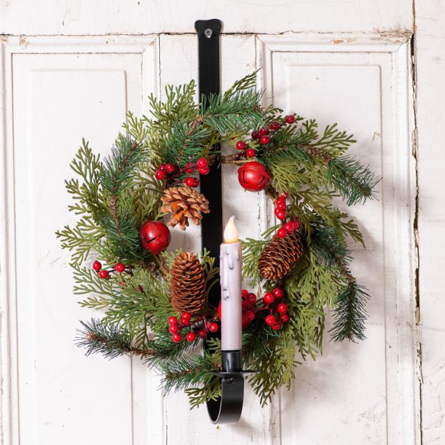 Wrought iron sconce with holiday wreath on a weathered wood background.