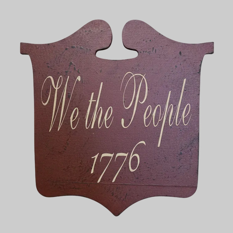 Decorative sign with 'We the People 1776' text on a gray background.