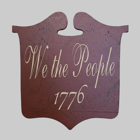 Decorative sign with 'We the People 1776' text on a gray background.