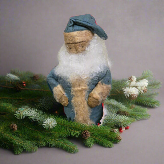 Stuffed Santa figure in a blue coat among greenery